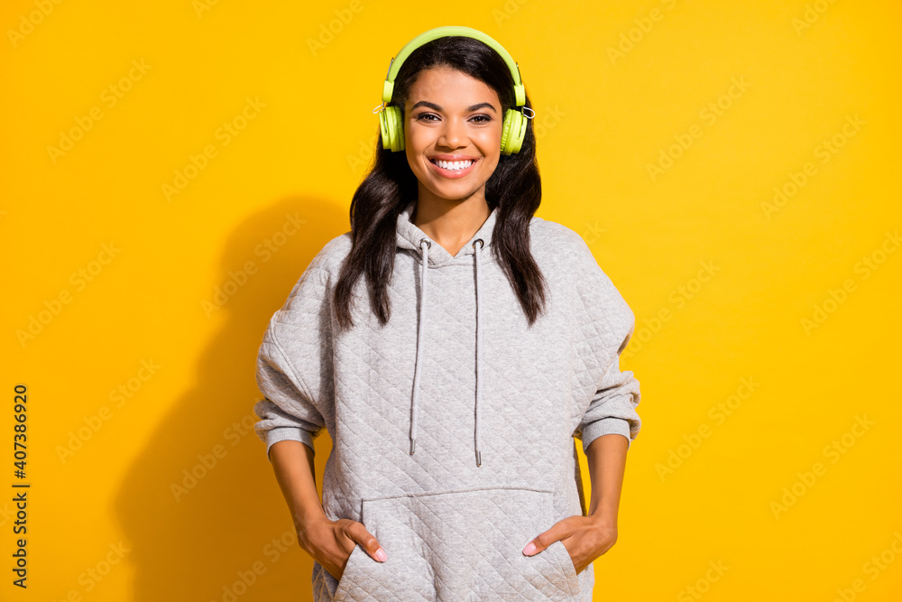 Sticker Photo of happy positive dark skin woman hold hands pockets wear headset isolated on yellow color background