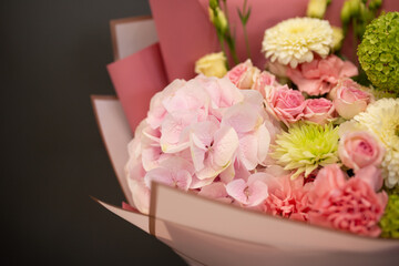 A bouquet of fresh flowers in decorative packaging. Photo on a dark background. Congratulatory bouquet.