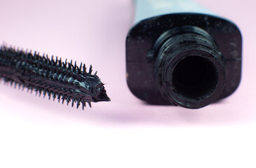 Mascara on eyelashes with brush on pink background..Make up, cosmetics, beauty. Close up, macro.