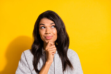 Photo of dreamy shiny dark skin girl dressed grey sweatshirt arm chin looking empty space isolated yellow color background