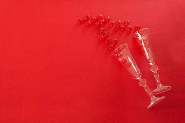 Champagne glasses and red hearts on red background . Valentine's day greeting card