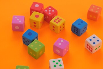 Board games. games of chance.  Multicolored cubes set close-up on a bright orange background.Figures and numbers concept. 