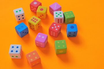 Board games concept. games of chance.  Multicolored cubes  close-up on a bright orange background.Figures and numbers concept. 