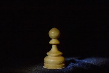 wooden chess pawn on a black background