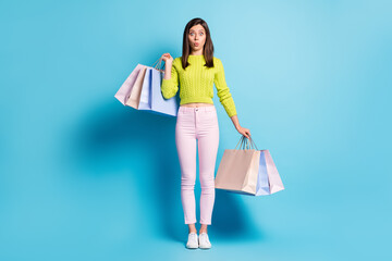 Full length photo portrait of shocked woman holding shopping bags isolated on pastel blue colored background
