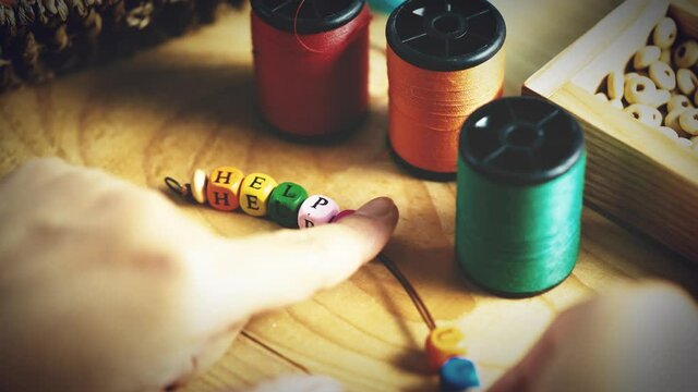 String a bracelet Wooden letter beads of helpful word, Close up woman hand string with a colourful Wooden letter beads, mood and tone concept.