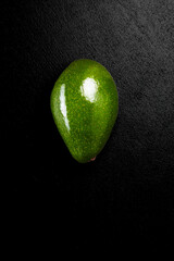green fresh avocado over black background close-up