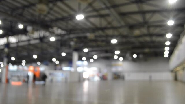 Blurred background. Inside big empty building with high ceiling.