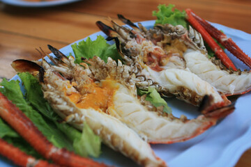 Grilled giant river prawn on white dish with spicy seafood sauce. Popular Thai food on wooden table as background