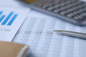 Metal ballpoint pen lying on documents in numbers on table closeup