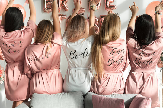Bride with girlfriends in silk robes at a bachelorette party.