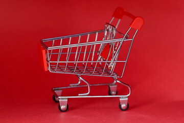 Miniature toy grocery cart standing on red background