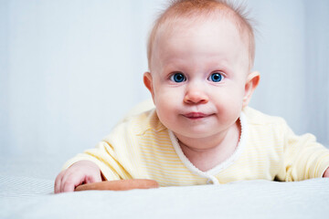 Portrait of a cute seven-month-old girl with blue eyes. A child plays with wooden toys in a bright room. Eco-friendly toys for children made from natural materials