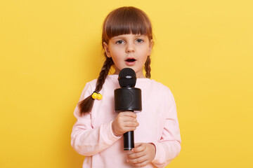 Small European female kid sing in microphone, looks concentrated, wants be great singer, little...