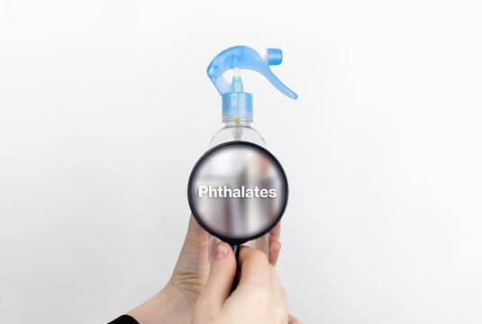 A woman examines the harmful ingredients of the air freshener through a magnifying glass. Means with phthalates. The concept of hazardous substances in cosmetics and household chemicals