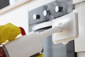 Hands in rubber gloves washing facades in kitchen with steamer closeup