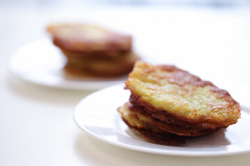 Potato latkes lying on white plate in cafe closeup