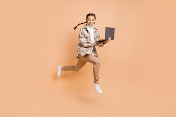 Fototapeta na wymiar Full size photo of young happy smiling excited positive girl running in air hold laptop isolated on beige color background