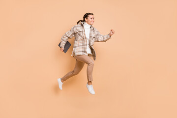 Fototapeta na wymiar Full size profile photo of impressed girl jump hold laptop wear white shirt trousers sneakers isolated on beige color background
