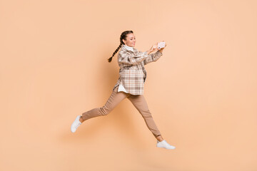Fototapeta na wymiar Full size profile photo of optimistic girl jump do photo wear white shirt trousers sneakers isolated on beige background