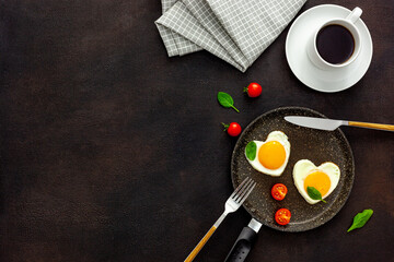 Cooking heart-shaped fried eggs in a pan with tomatoes and greens