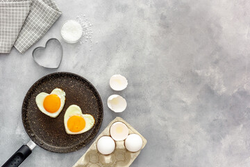 Cooking heart-shaped fried eggs in a pan