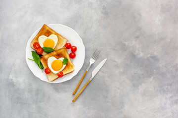 Scrambled eggs in the form of heart on plate with tomatoes, greens and coffee