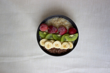 Porridge with banana, kiwi, strawberries,
flax seeds isolated on  background. Oatmeal. Healthy lifestyle. Ketogenic diet. Dessert. Meal.