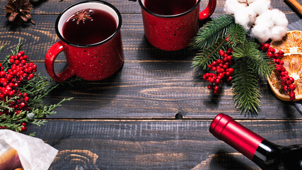 Bottle, mugs and ingridients for mulled wine on wooden dark table. Winter hot beverage with dry oranges, cinnamon, sugar. Copy space for your text
