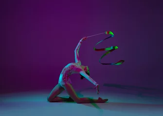 Foto op Canvas Wave. Young female athlete, rhythmic gymnastics artist dancing, training with tape isolated on purple studio background in neon light. Beautiful girl practicing with equipment. Grace in performance. © master1305