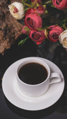 Cup of coffee and flowers. An invitation to a romantic evening. Hearts bokeh, red light effect. Vintage background for postcards.