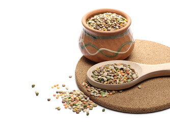 Mixed legumes, cereals on round cork mat with clay bowl andwooden spoon, peeled barley, green, yellow and dark red lentils, half green peas, black white beans, green beans isolated on white background