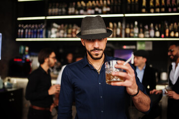 Stylish arab man against group of handsome retro well-dressed guys gangsters spend time at club, drinking on bar counter. Multiethnic male bachelor mafia party in restaurant.