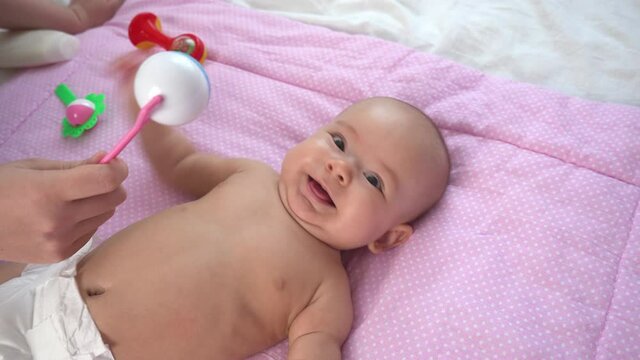 Mom plays with a newborn rattle toy. Newborn baby