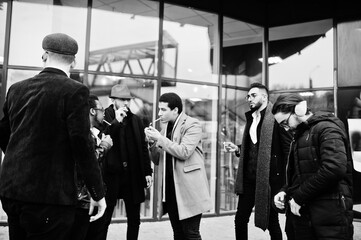 Group of handsome retro well-dressed man gangsters smoking outdoor. Multiethnic male bachelor mafia party.