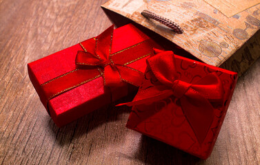 Two wrapping presents in craft gift bag on wooden background. long and square red gift boxes tied in red ribbon bow. holiday concept. valentines day. surprise for lovely woman. shopping sale