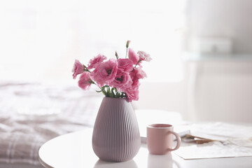 Fototapeta na wymiar Vase with beautiful eustoma flowers on table in modern room interior