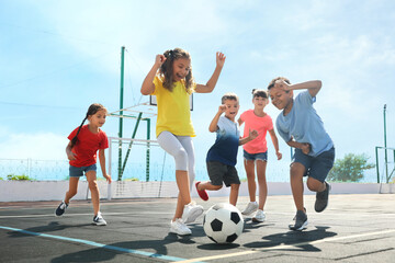 Cute children playing soccer outdoors on sunny day. Summer camp