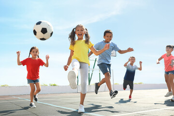 Cute children playing soccer outdoors on sunny day. Summer camp