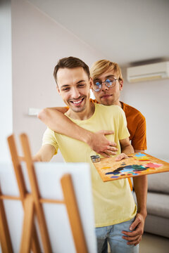 Happy Gay Couple Painting Picture At Home