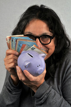 Femme radine tenant une tirelire et de billets de banque en main