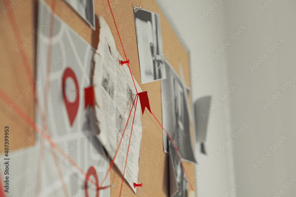 Sticker detective board with crime scene photos and red threads, closeup