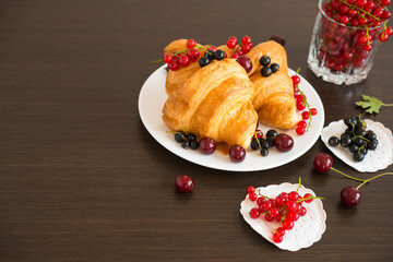 Sweet rolls. Berries. Fresh croissants and ripe red currants, black currants, cherries.
