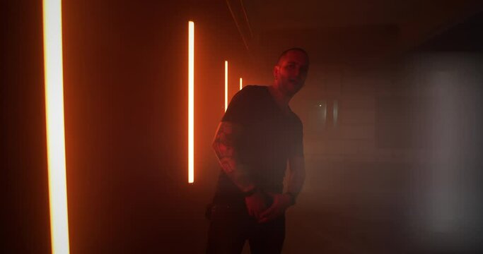 Male rapper walking near red lamps