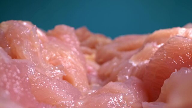 extremely close-up, detailed. sliced chicken fillet on a blue background.