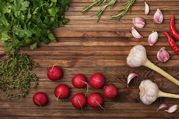 Fototapeta na wymiar On a wooden kitchen table are laid out radish, garlic, parsley rosemary and micro green