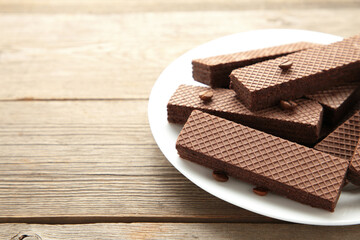 Chocolate wafers with coffee in plate on grey wooden background.