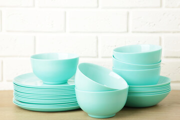 Stacks of mint ceramic dishware on light background