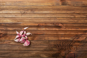 there are cloves of garlic on a wooden table in the left corner