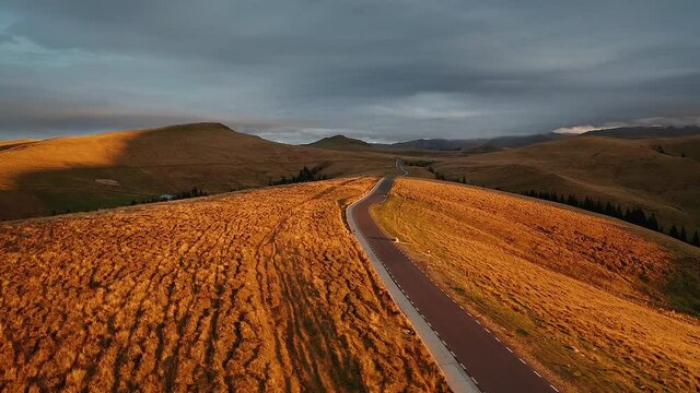 4K Aerial view of a beautiful sunrise over Transbucegi curved road in the mountains of Romania